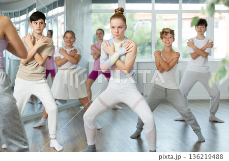 Female girl student repeats movements of unrecognizable teacher during group modern dance class. Female girl student repeats movements of unrecognizable teacher during group modern dance class. 136219488