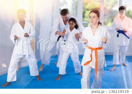 Tween girl practicing punches during group martial arts workout 136219519