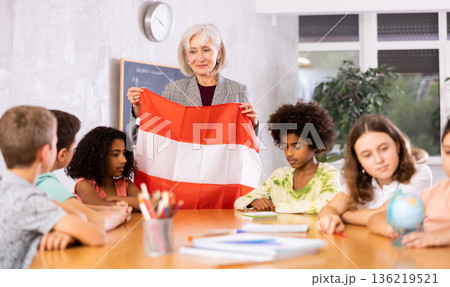 Female teacher showing austrian flag to kids in geography class 136219521