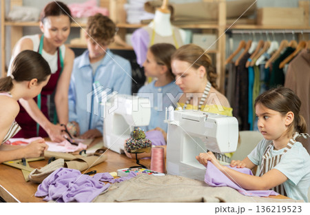Preteen girl stitching at machine during sewing class for children Preteen girl stitching at machine during sewing class for children 136219523