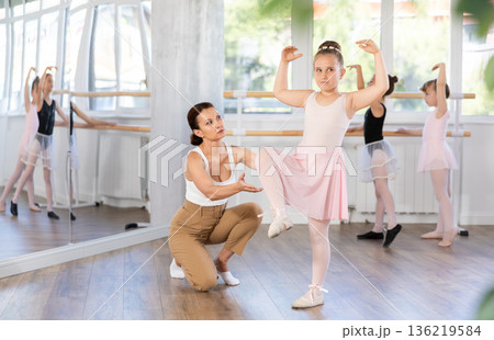 Woman teacher corrects movement of girl dancer Woman teacher corrects movement of girl dancer 136219584