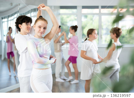 Group of teenagers, girls and boys, dance a slow ballroom dance in choreography studio Group of teenagers, girls and boys, dance a slow ballroom dance in choreography studio 136219597