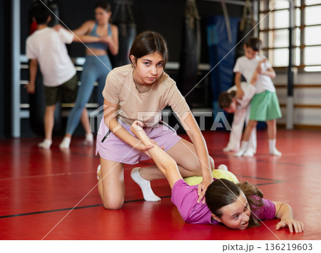 Purposeful engrossed teen girls train during self-defense fight training session in gym Purposeful engrossed teen girls train during self-defense fight training session in gym 136219603
