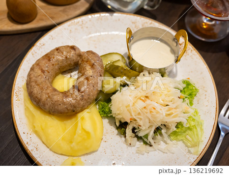 Pork sausages with mashed potatoes, horseradish sauce and cucumbers 136219692