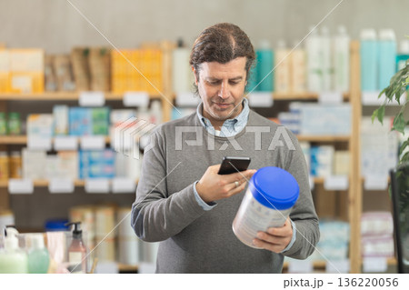 Man in pharmacy scans QR code on infant formula product 136220056