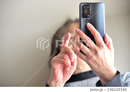 携帯電話を操作するシニア女性 136220380