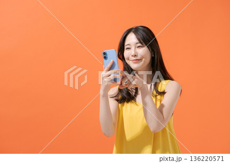 スマホを持つ笑顔の女性 136220571