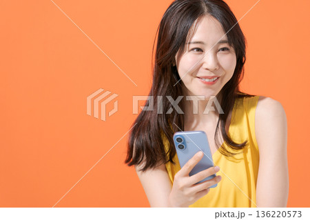 スマホを持つ笑顔の女性 136220573