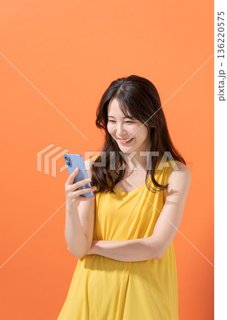 スマホを持つ笑顔の女性 136220575