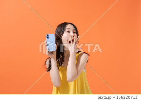 スマホを持つ驚いた表情の女性 136220713