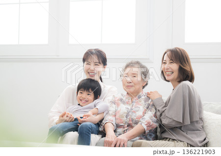 逆光の綺麗な部屋で祖母と母と子ども(ひ孫）が笑顔で抱き合う四世代家族、親子の幸せな記念写真 136221903