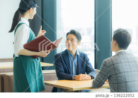 カフェで注文をとるスタッフ 136222052