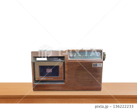 A vintage-style retro portable radio sits on a wooden table against a white background. A vintage-style retro portable radio sits on a wooden table against a white background. 136222233