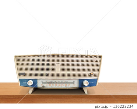 An antique cream and blue radio sits on a wooden table against a white background. An antique cream and blue radio sits on a wooden table against a white background. 136222234