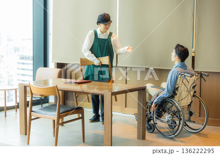 カフェで車椅子のお客さんを案内するスタッフ カフェで車椅子のお客さんを案内するスタッフ 136222295