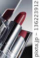 Luxury matte red lipstick in silver metallic tube with mirror reflections and minimalist aesthetic, close-up. 136223912