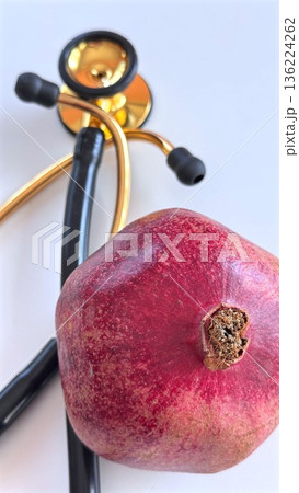 Medical Equipment And Pomegranate Illustrate Wellness And Body Care Themes. Image Pairs Traditional Stethoscope With Pomegranate To Symbolize Health And Digestion Benefits Medical Equipment And Pomegranate Illustrate Wellness And Body Care Themes. Image Pairs Traditional Stethoscope With Pomegranate To Symbolize Health And Digestion Benefits 136224262