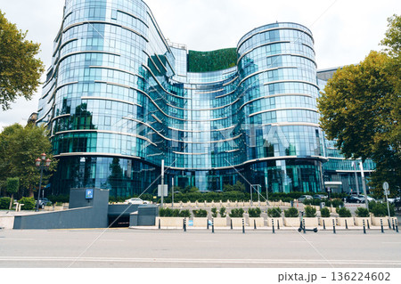 Modern building with glass facade located in a city during a cloudy day Modern building with glass facade located in a city during a cloudy day 136224602