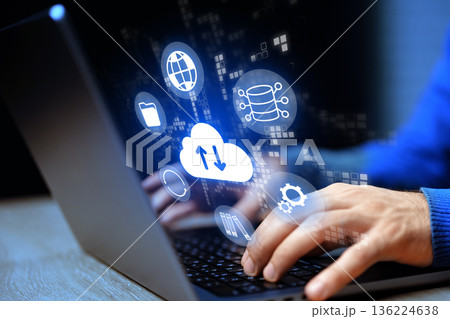 Working on a laptop with cloud storage icons at night in a modern setting with technology 136224638