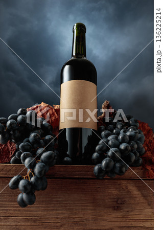 Red wine bottle with blue grapes on a background of cloudy sky. 136225214