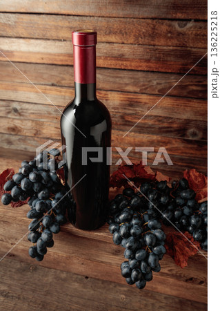 Red wine bottle with blue grapes on an old wooden table. Red wine bottle with blue grapes on an old wooden table. 136225218