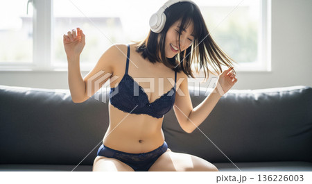 ソファーでヘッドホンをして髪を揺らし楽しむ日本人女性 136226003