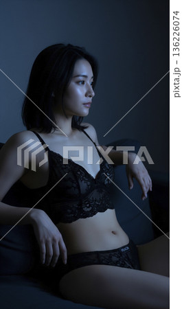 テレビの光に照らされた黒いランジェリー姿の日本人女性 136226074