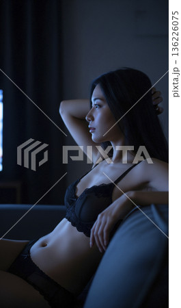ソファーでくつろぎながらテレビを見る黒い下着姿の女性 136226075