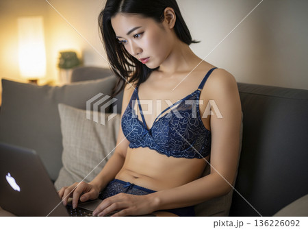 夜のリビングでノートパソコンを作業するランジェリー姿の女性 136226092