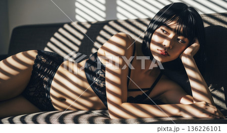 ストライプ状の影が落ちる室内で物思いにふける下着姿の女性 136226101