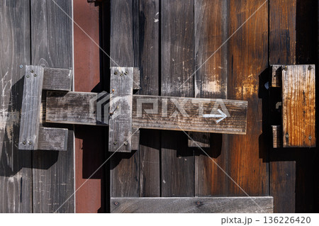 矢印が描かれた古い木戸の鍵（かんぬき）と質感 136226420
