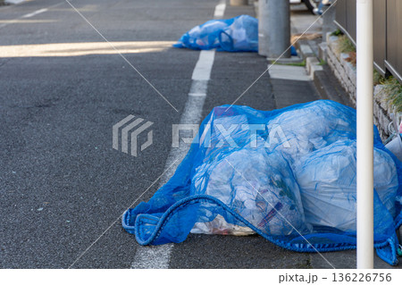 路上にまとめられた青い防鳥ネットとゴミ袋 136226756