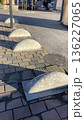 Rounded concrete bollards are aligned along a paved walkway, serving as barriers to prevent vehicle access on sidewalks.  136227065