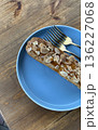 Uncut almond pastry topped with sliced almonds, placed on a vibrant blue plate with two forks beside it.  136227068