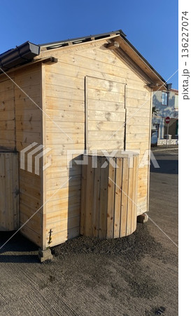 A small wooden booth or kiosk with a curved outdoor counter, closed and unstaffed, in an open paved area.  136227074