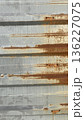 Close-up of a gray corrugated metal wall with brown rust lines and aged texture, ideal for industrial backgrounds.  136227075