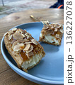 Close-up of a sliced almond pastry on a blue plate with two forks, suggesting a shared sweet treat moment.  136227078