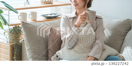 リビングのソファーに座りホットドリンクを飲むオシャレな女性 リビングのソファーに座りホットドリンクを飲むオシャレな女性 136227242