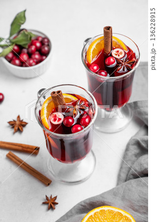 Two glasses of mulled wine, orange, cranberry, cinnamon, and star anise on a light background 136228915