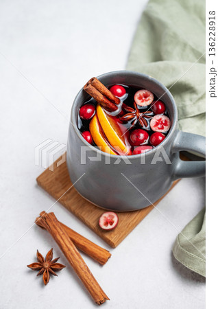 A cup of red mulled wine with cinnamon, orange and cranberry on a wooden board A cup of red mulled wine with cinnamon, orange and cranberry on a wooden board 136228918
