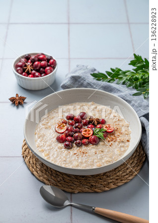 Oatmeal with cranberry, cinnamon and spicy in a plate on a blue tile background Oatmeal with cranberry, cinnamon and spicy in a plate on a blue tile background 136228923