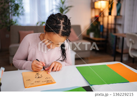 Girl drawing Mother's Day card for mom 136229215