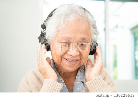Asian senior woman patient happy to use earphone to listen relax music. 136229618