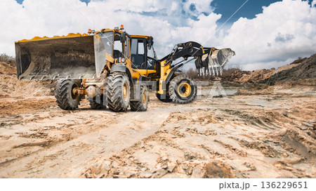 At the construction site there are earth embankments, Two powerful wheel loaders are planning the earth foundation At the construction site there are earth embankments, Two powerful wheel loaders are planning the earth foundation 136229651