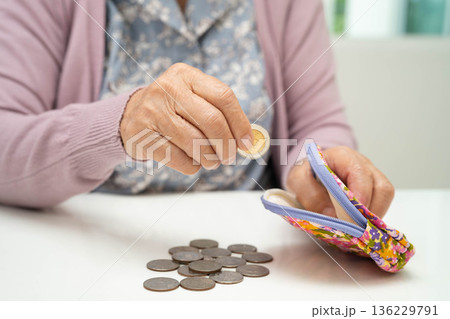 Asian senior or elderly old lady woman holding counting coin money in bag. Poverty, saving problem in retirement. Asian senior or elderly old lady woman holding counting coin money in bag. Poverty, saving problem in retirement. 136229791