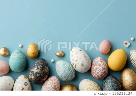 Assorted colored decorative Easter eggs laid out on a light blue surface, with various patterns and textures 136231124