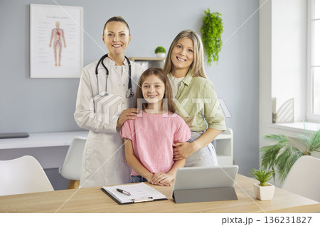 Family pediatric visit with smiling doctor, mother and daughter in bright clinic 136231827