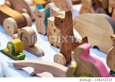 Hand-carved wooden toys on display on a table at a craft fair 136232213