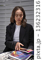 Elegant businesswoman sitting outdoors reading a colorful magazine 136232316