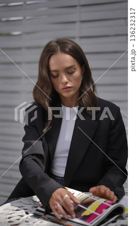 Young stylish woman reading a fashion magazine outdoors at a cafe Young stylish woman reading a fashion magazine outdoors at a cafe 136232317